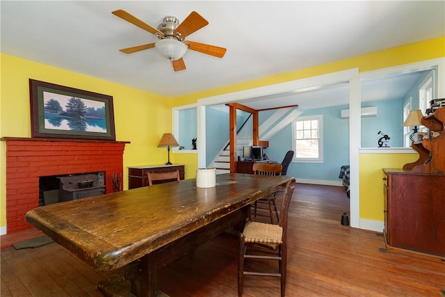 dining area with ceiling fan, a wall mounted air conditioner, wood-type flooring, a fireplace, and pool table