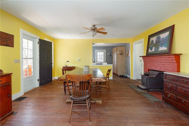 dining area featuring a wood stove, ceiling fan, and hardwood / wood-style flooring