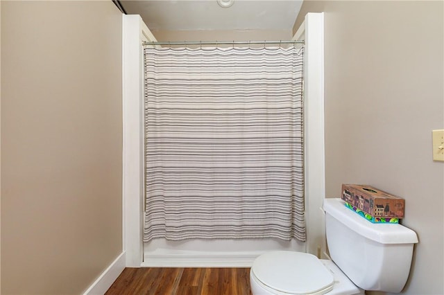 bathroom featuring hardwood / wood-style floors, toilet, and a shower with shower curtain