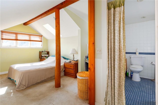 carpeted bedroom featuring ensuite bath, vaulted ceiling with skylight, and tile walls