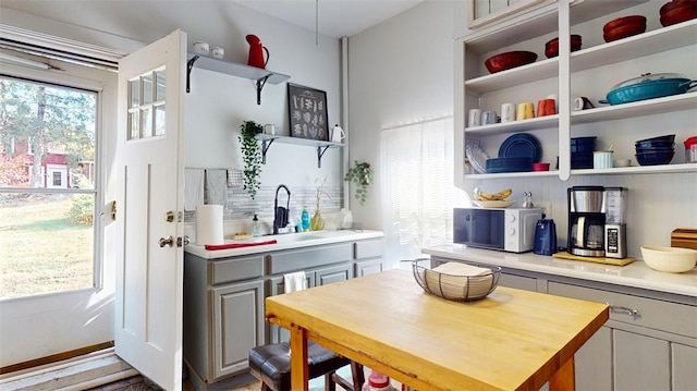 kitchen featuring gray cabinetry, a kitchen island, a wealth of natural light, and wooden counters