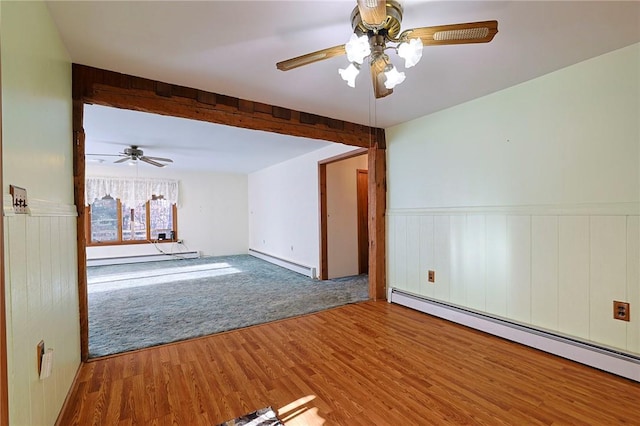 spare room featuring hardwood / wood-style flooring, ceiling fan, and a baseboard heating unit