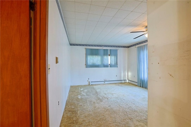 carpeted empty room featuring crown molding, ceiling fan, and a baseboard heating unit