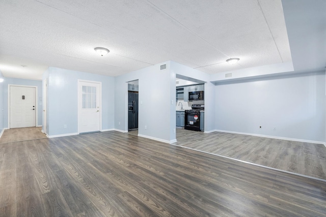 unfurnished living room with dark hardwood / wood-style floors, sink, and a textured ceiling