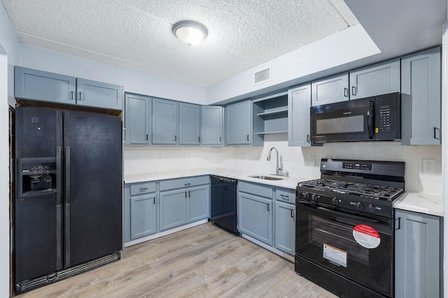 kitchen featuring a textured ceiling, sink, light hardwood / wood-style floors, and black appliances