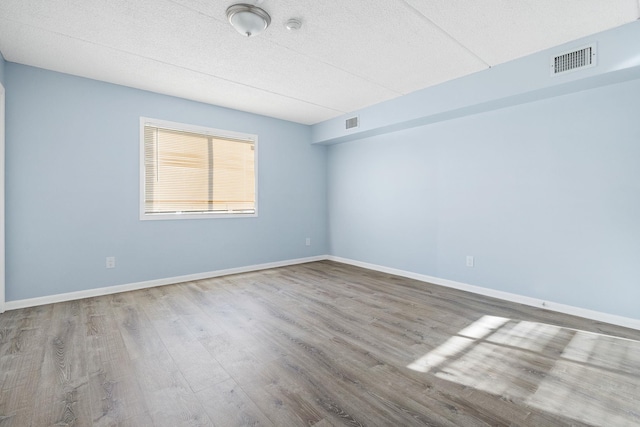 spare room featuring wood-type flooring and a textured ceiling