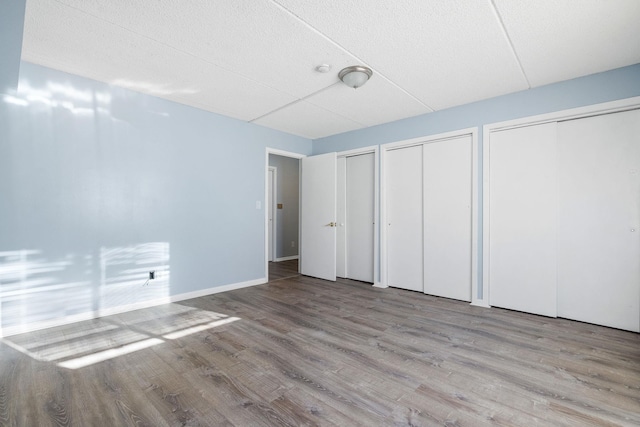 unfurnished bedroom with wood-type flooring and two closets