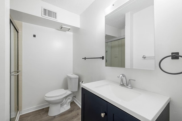 bathroom featuring walk in shower, vanity, a textured ceiling, hardwood / wood-style flooring, and toilet