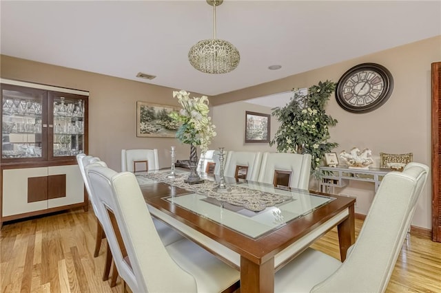 dining room featuring light wood-type flooring and an inviting chandelier