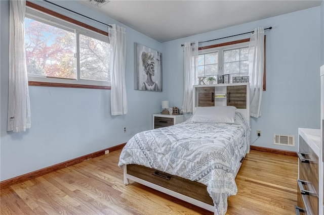 bedroom with light hardwood / wood-style floors and multiple windows