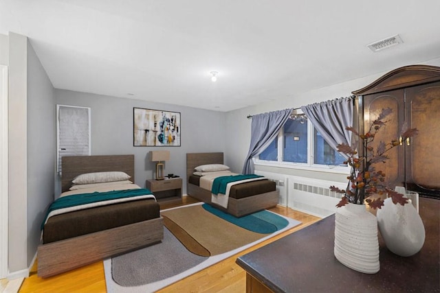 bedroom featuring radiator heating unit and light hardwood / wood-style floors