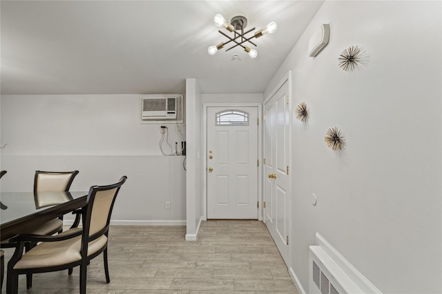 entryway with an AC wall unit, light hardwood / wood-style flooring, and an inviting chandelier