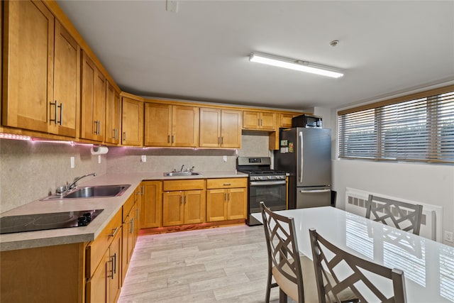 kitchen with decorative backsplash, sink, light hardwood / wood-style floors, and appliances with stainless steel finishes