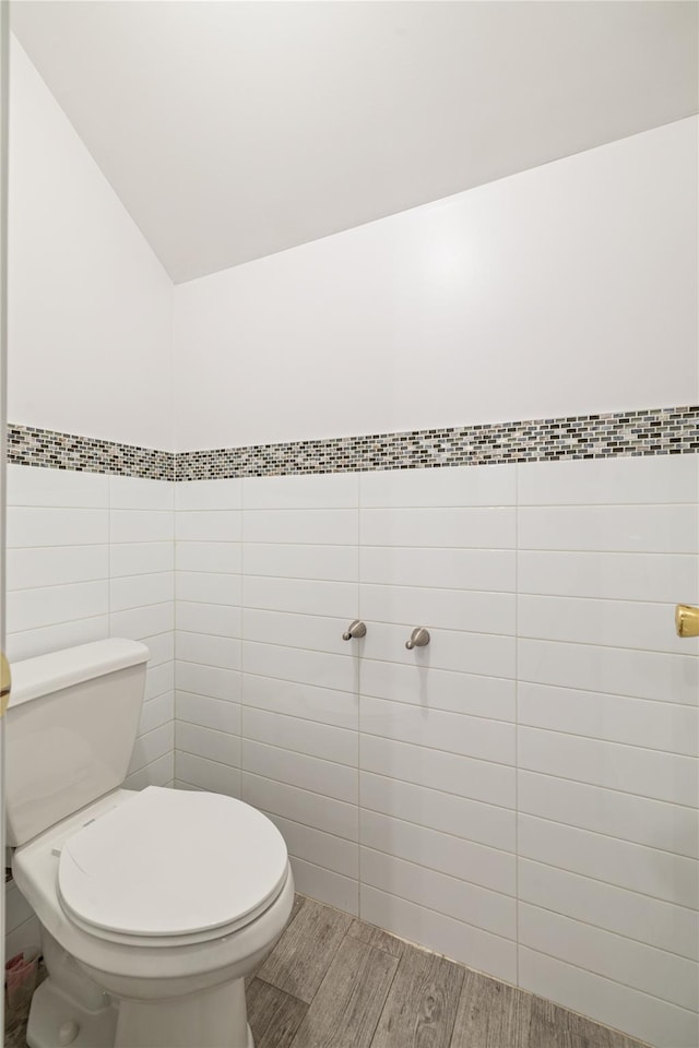 bathroom featuring wood-type flooring, tile walls, and toilet