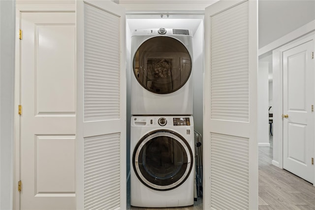 washroom with light hardwood / wood-style floors and stacked washing maching and dryer