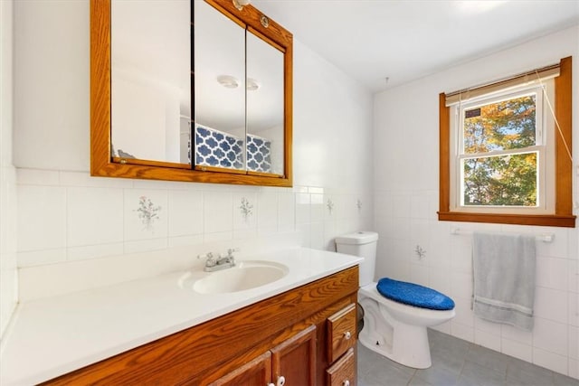 bathroom with tile patterned flooring, vanity, toilet, and tile walls