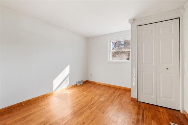 unfurnished bedroom with crown molding, a closet, and wood-type flooring