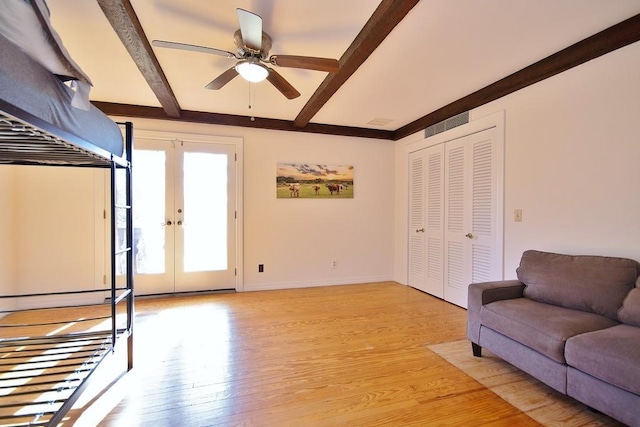 unfurnished living room featuring beamed ceiling, french doors, light hardwood / wood-style floors, and ceiling fan