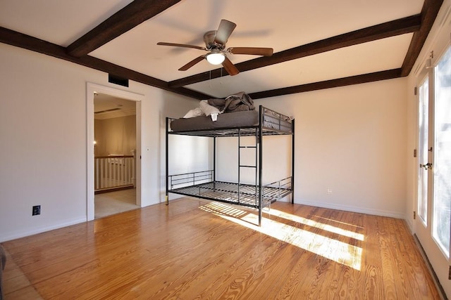 unfurnished bedroom featuring beamed ceiling, light hardwood / wood-style floors, multiple windows, and ceiling fan