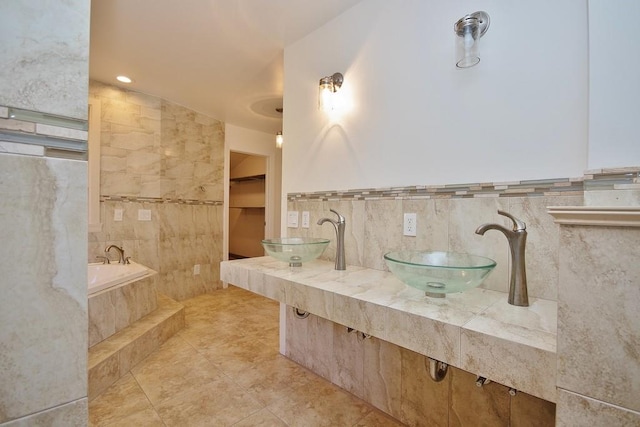 bathroom with tile patterned flooring, vanity, tile walls, and tiled tub