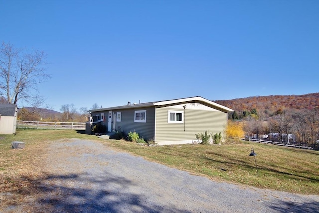 view of side of property with a mountain view and a yard