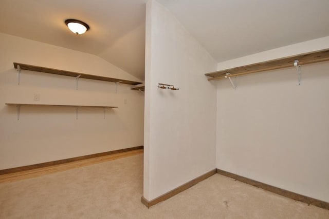 walk in closet featuring light carpet and vaulted ceiling