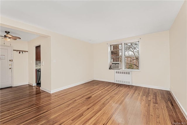 unfurnished room featuring cooling unit, radiator heating unit, baseboards, and wood finished floors