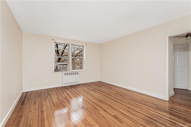 spare room with radiator, baseboards, and wood finished floors