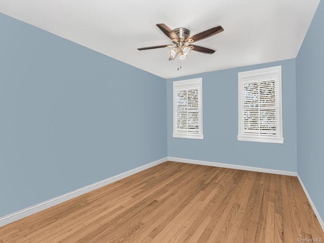 spare room featuring light wood-style floors, baseboards, and a ceiling fan