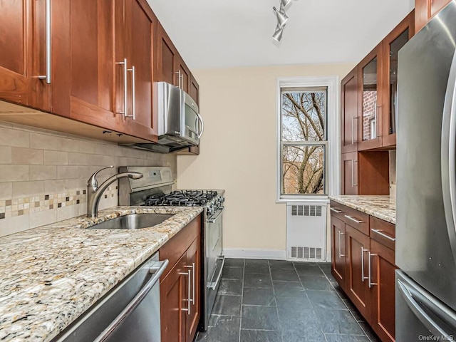 kitchen featuring appliances with stainless steel finishes, radiator heating unit, a sink, and light stone countertops