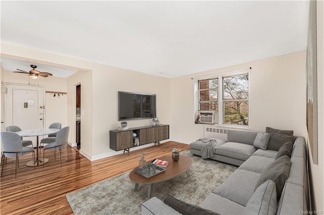 living room with a ceiling fan, baseboards, cooling unit, and wood finished floors