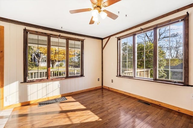 empty room featuring hardwood / wood-style floors, ceiling fan, and crown molding