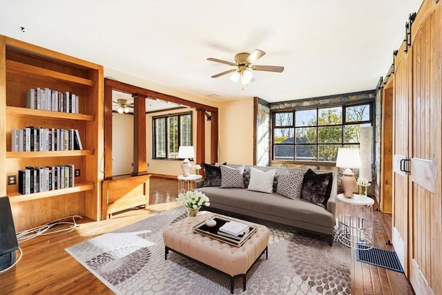 living room featuring a barn door, hardwood / wood-style flooring, and ceiling fan