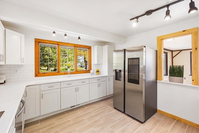 kitchen with white cabinets, stainless steel refrigerator with ice dispenser, decorative backsplash, and light stone countertops