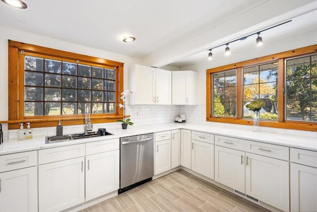 kitchen featuring dishwasher, sink, light wood-type flooring, tasteful backsplash, and white cabinetry