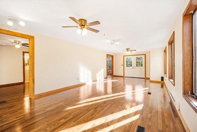 spare room featuring wood-type flooring, baseboard heating, and french doors