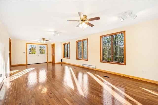 spare room featuring baseboard heating, plenty of natural light, and hardwood / wood-style floors