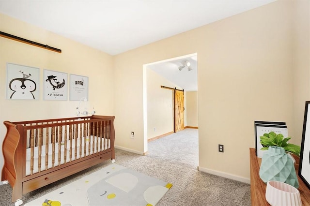 carpeted bedroom featuring a barn door and a nursery area