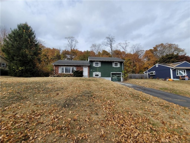 split level home featuring a garage and a front lawn