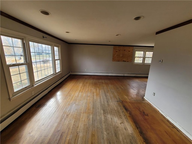 empty room featuring hardwood / wood-style floors, crown molding, and a baseboard radiator