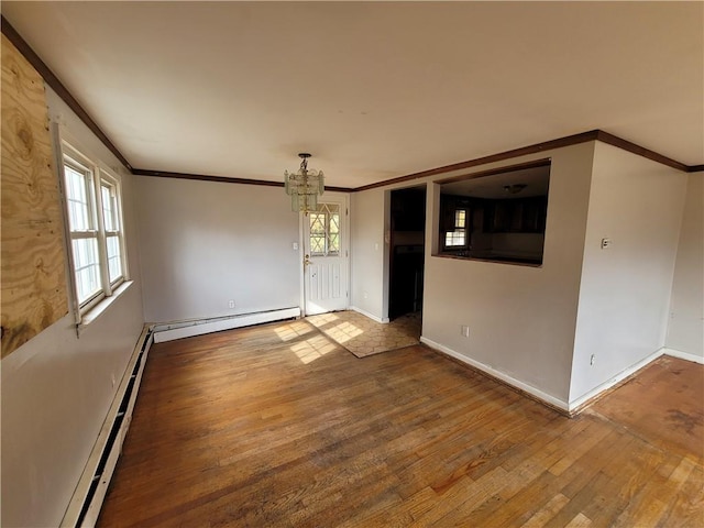 empty room featuring hardwood / wood-style flooring, plenty of natural light, and a baseboard heating unit