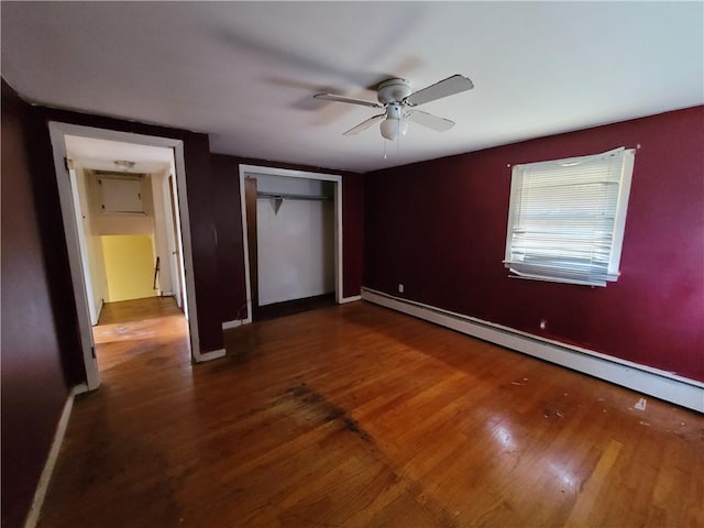 unfurnished bedroom featuring ceiling fan, wood-type flooring, baseboard heating, and a closet