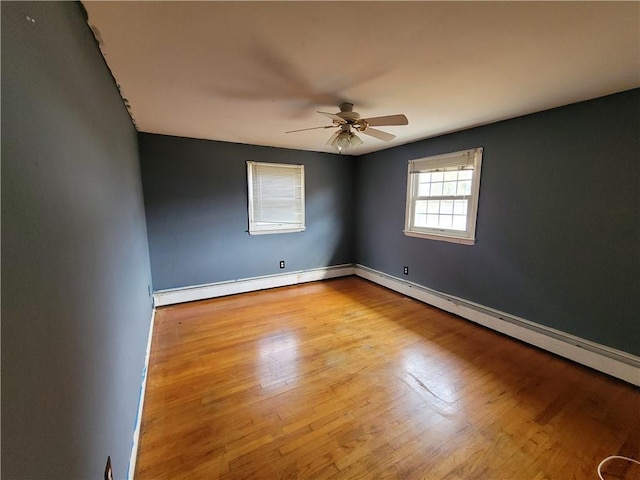 empty room featuring hardwood / wood-style floors, ceiling fan, and a baseboard heating unit