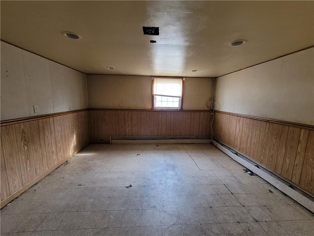 spare room featuring wooden walls and a baseboard heating unit