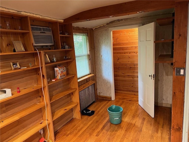 interior space featuring radiator heating unit, light hardwood / wood-style flooring, an AC wall unit, and wood walls