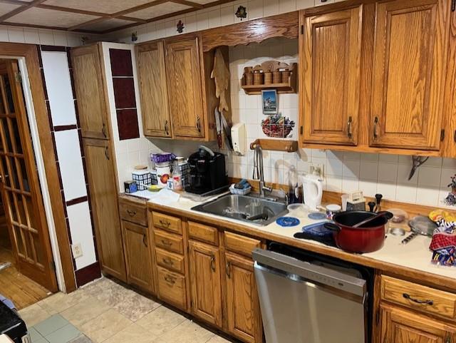 kitchen featuring stainless steel dishwasher, backsplash, and sink