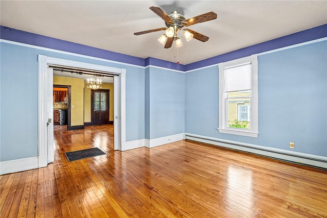 unfurnished room featuring ceiling fan with notable chandelier, hardwood / wood-style flooring, and baseboard heating