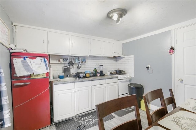 kitchen featuring decorative backsplash, white cabinetry, fridge, and white gas range oven