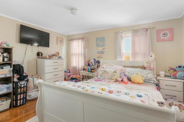 bedroom featuring multiple windows, crown molding, and light hardwood / wood-style floors