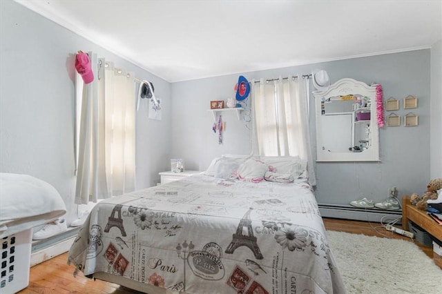 bedroom with hardwood / wood-style flooring, a baseboard radiator, and ornamental molding